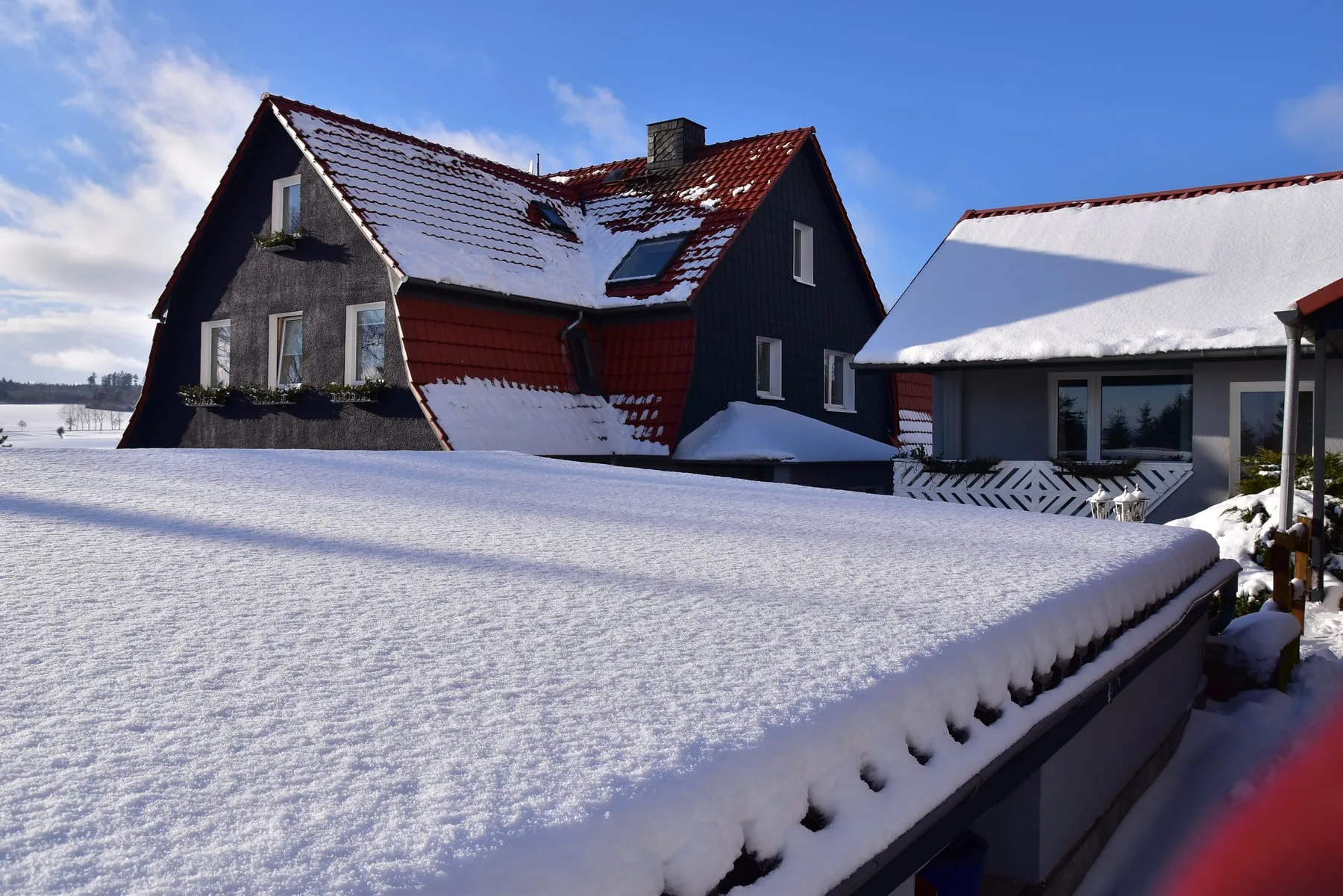 Pension Volgenandt im Winter mit tiefem Schnee und blauem Himmel