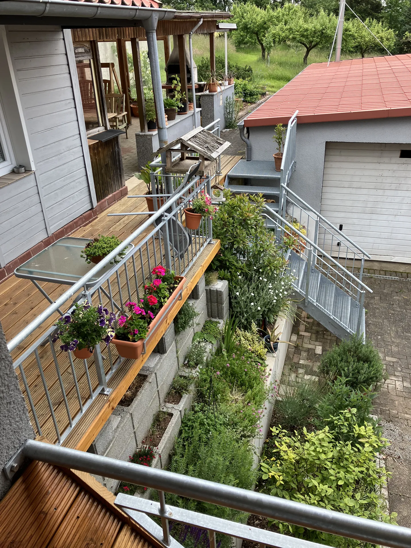 Blick vom Balkon auf Terrasse und Kräuterbeet