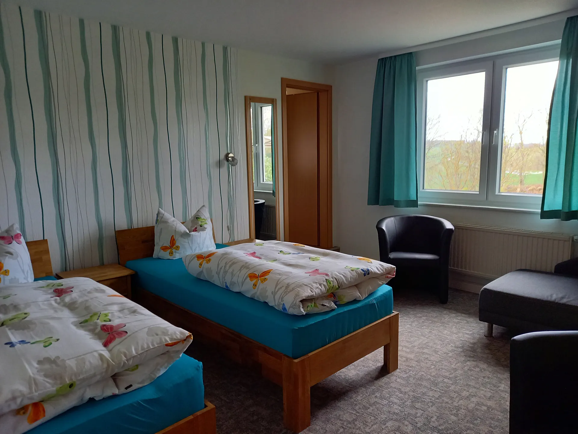 Zimmeransicht mit Fensterblick ins Grüne und Sessel